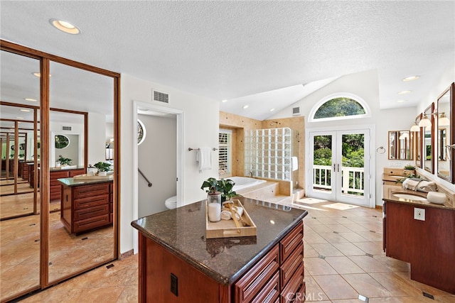 kitchen with french doors, a sink, dark stone counters, open floor plan, and lofted ceiling
