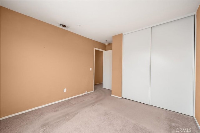 unfurnished bedroom with carpet floors, baseboards, a closet, and visible vents