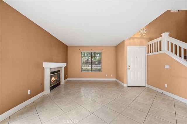 unfurnished living room with baseboards, a fireplace, and light tile patterned flooring