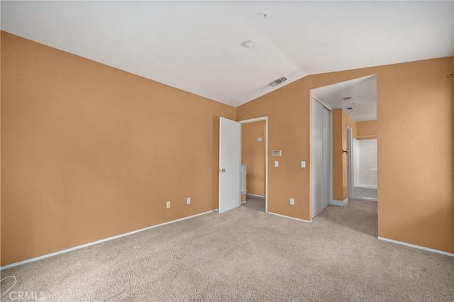 unfurnished bedroom with visible vents, baseboards, lofted ceiling, and light colored carpet