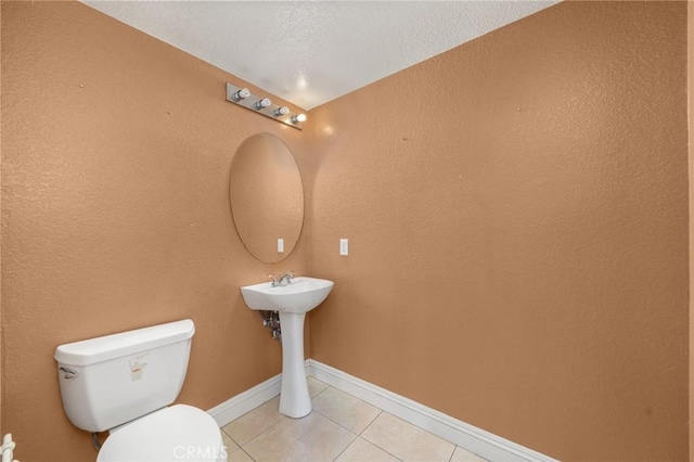 bathroom featuring toilet, baseboards, and tile patterned flooring