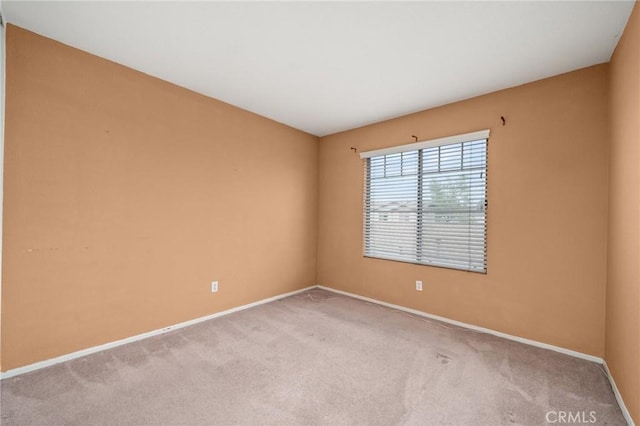 spare room with baseboards and light carpet
