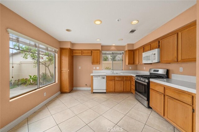 kitchen featuring a healthy amount of sunlight, brown cabinetry, and white appliances