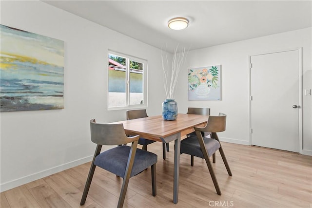 dining space featuring baseboards and light wood-style flooring