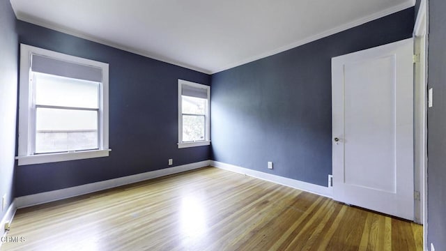 unfurnished room featuring crown molding, baseboards, and wood finished floors