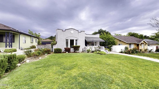 mediterranean / spanish-style house with fence and a front yard