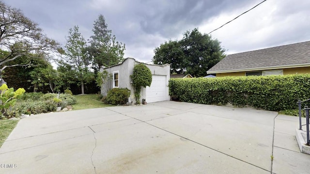 view of patio / terrace with an outdoor structure, an attached garage, and driveway
