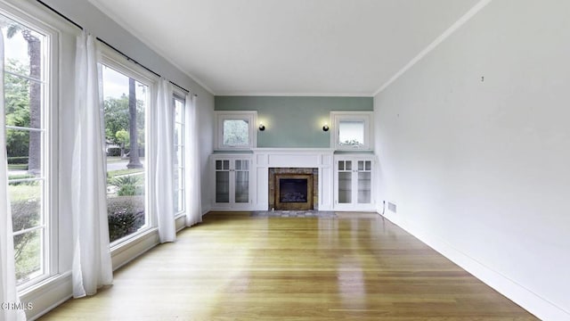 unfurnished living room featuring crown molding, light wood finished floors, and a wealth of natural light