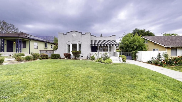 mediterranean / spanish-style home featuring fence, stucco siding, driveway, and a front yard
