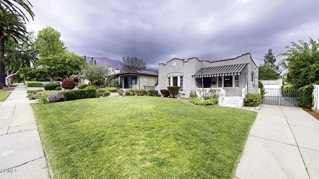 mediterranean / spanish house featuring fence, a gate, stucco siding, and a front yard