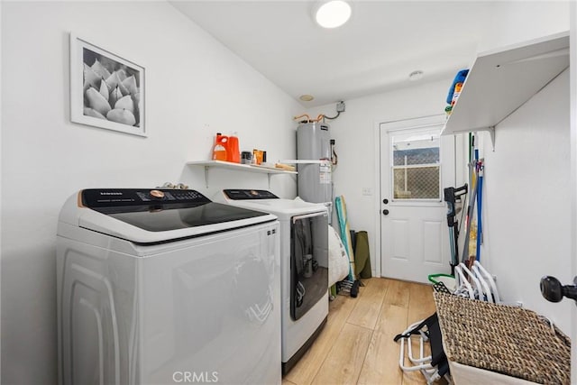 laundry area with laundry area, washer and clothes dryer, light wood-style floors, and water heater