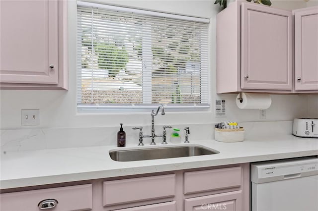 kitchen with white dishwasher, white cabinetry, and a sink
