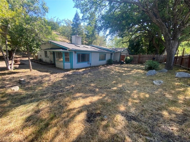 rear view of property with fence and a chimney