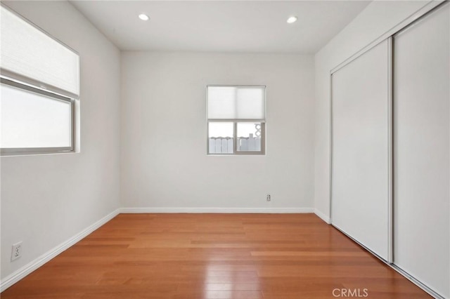 unfurnished bedroom with light wood-style floors, baseboards, a closet, and recessed lighting