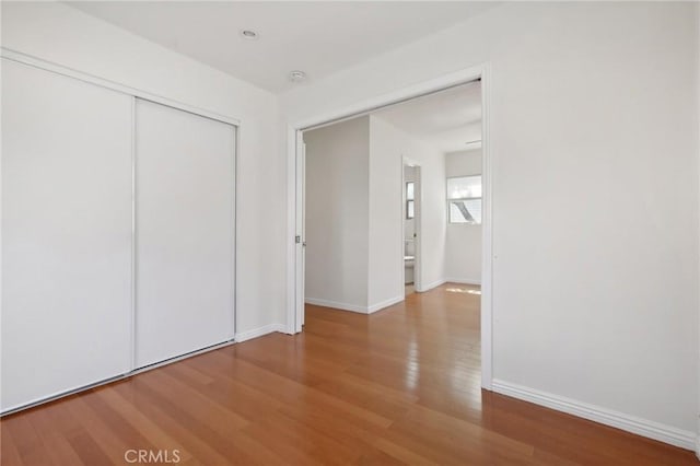 unfurnished bedroom featuring a closet, baseboards, and wood finished floors
