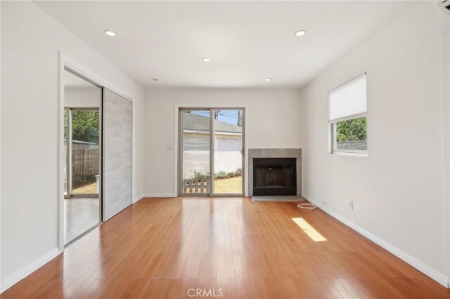 unfurnished living room with plenty of natural light, a fireplace, and light wood-style flooring