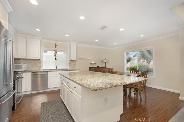 kitchen with backsplash, stainless steel appliances, plenty of natural light, and a kitchen island