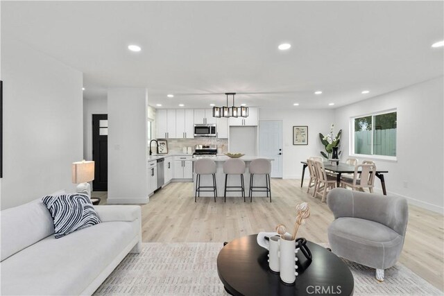 living area featuring recessed lighting, baseboards, and light wood-style flooring