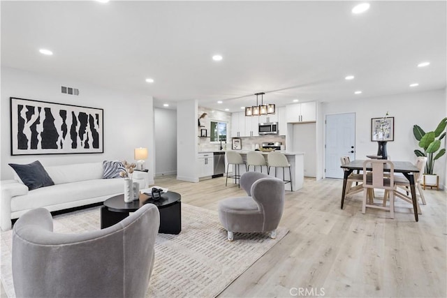 living area featuring light wood-style floors, baseboards, recessed lighting, and visible vents