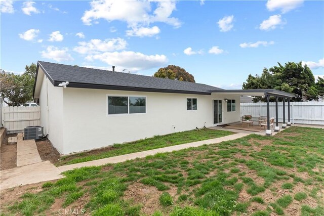 back of property with fence, stucco siding, a patio area, central air condition unit, and a lawn
