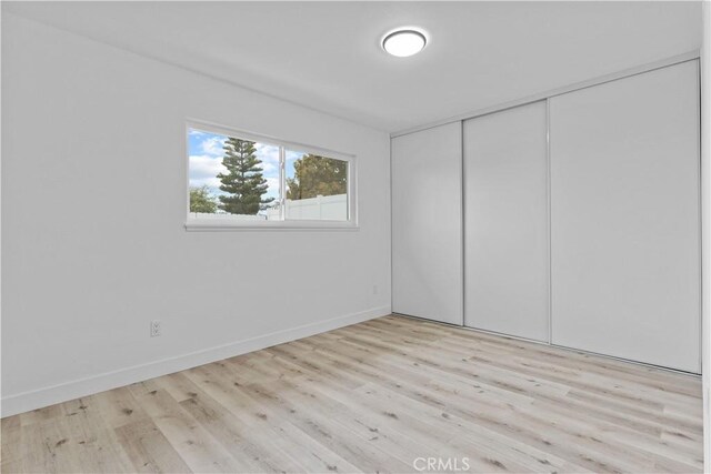 unfurnished bedroom with a closet, baseboards, and wood finished floors
