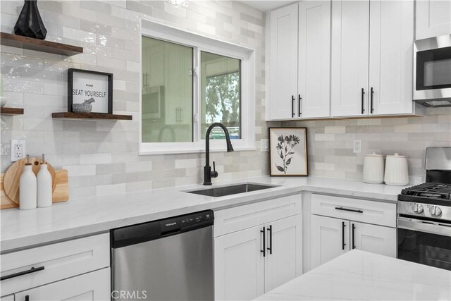 kitchen with backsplash, stainless steel appliances, open shelves, and a sink