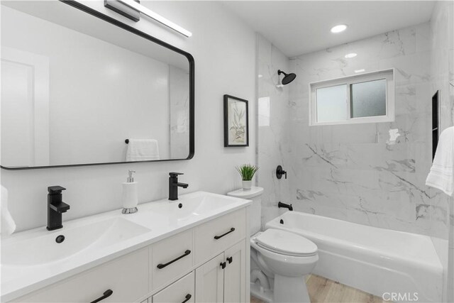 full bathroom with double vanity, wood finished floors, shower / washtub combination, a sink, and toilet
