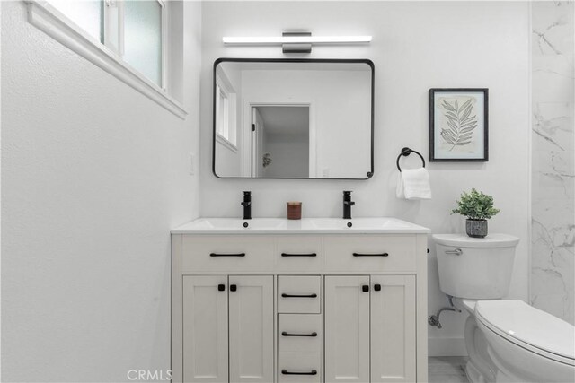 bathroom featuring a sink, toilet, double vanity, and marble finish floor