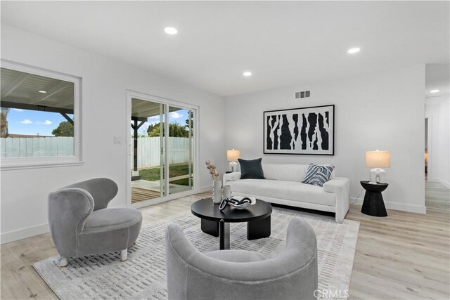 living room with recessed lighting, baseboards, light wood finished floors, and visible vents