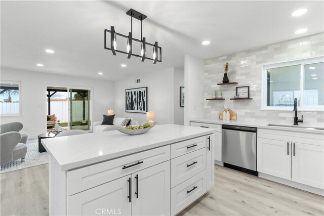 kitchen with a sink, backsplash, open floor plan, and dishwasher