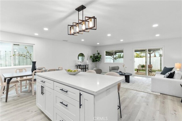 kitchen with light wood finished floors, a breakfast bar, recessed lighting, and open floor plan