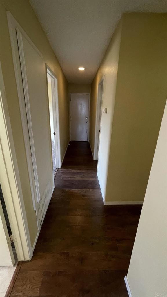 corridor featuring baseboards, recessed lighting, and dark wood-type flooring