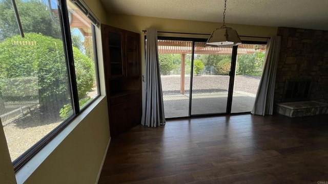 unfurnished dining area with a fireplace, a textured ceiling, and dark wood-type flooring