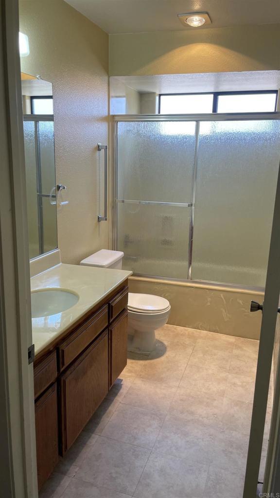 bathroom with toilet, enclosed tub / shower combo, and vanity