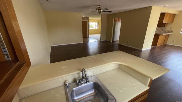 kitchen with a sink, dark wood finished floors, a ceiling fan, and freestanding refrigerator
