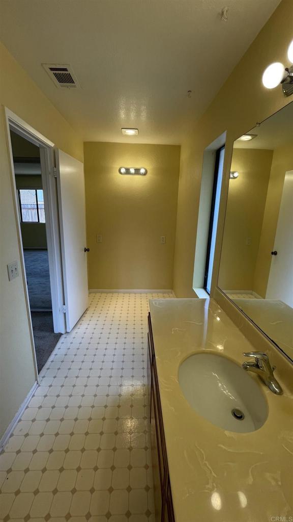 bathroom featuring baseboards, vanity, tile patterned floors, and visible vents