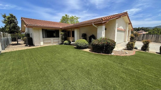 rear view of house featuring an attached garage, a lawn, fence, and a tiled roof