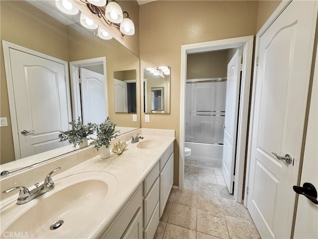 full bath featuring stone tile flooring, a sink, double vanity, and toilet