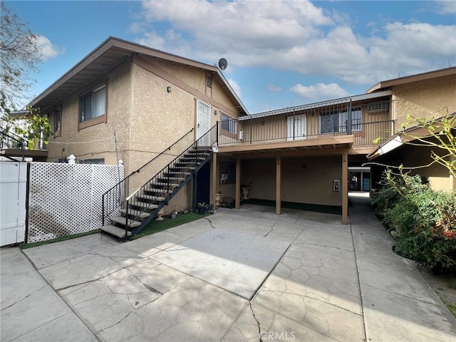 1908 E Coral Ave, Orange, CA 92865 - rear view of house featuring driveway, a wooden deck, a patio area, stairs, and stucco siding
