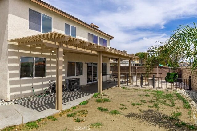 rear view of property with a pergola, stucco siding, a fenced backyard, central AC unit, and a patio