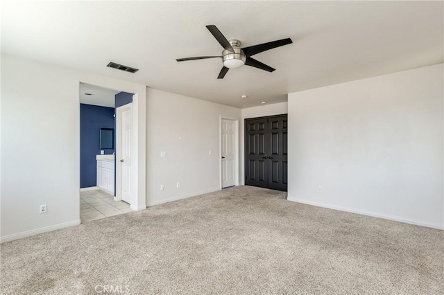 unfurnished room featuring baseboards, ceiling fan, light carpet, and visible vents