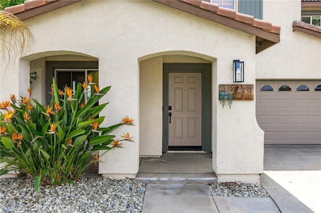 view of exterior entry featuring a garage and stucco siding