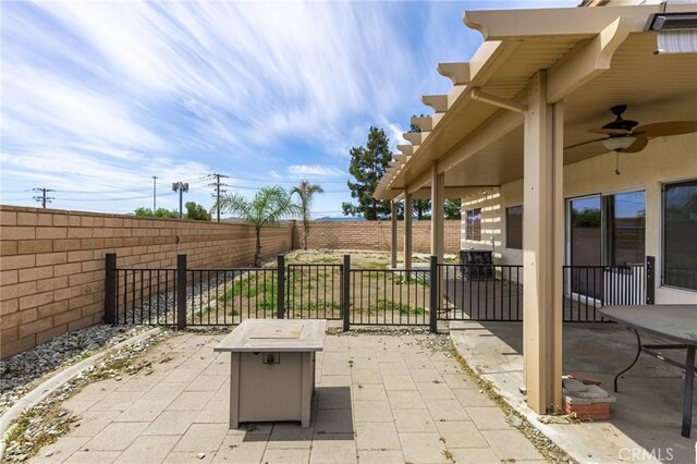 view of patio featuring ceiling fan, a fire pit, and a fenced backyard