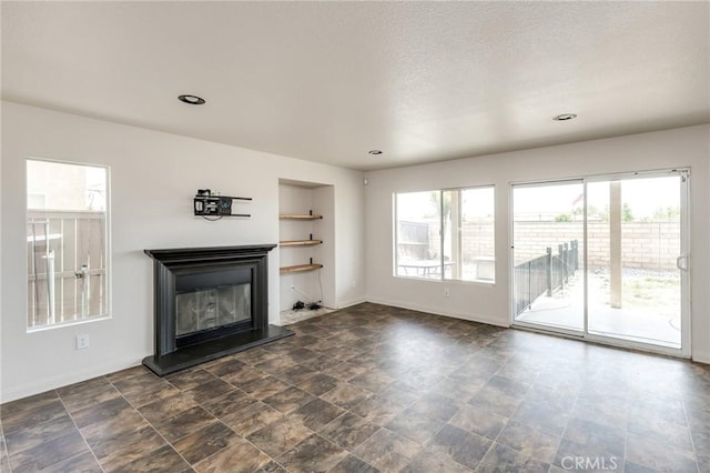 unfurnished living room with baseboards, recessed lighting, and a glass covered fireplace