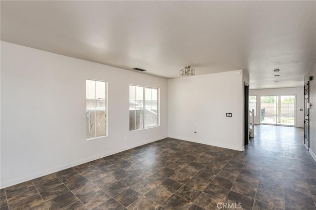 unfurnished room with baseboards, stone finish floor, and visible vents