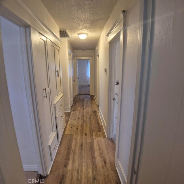 804 S Mayo Ave, Compton, CA 90221 - hallway featuring a textured ceiling, visible vents, dark wood-style flooring, and baseboards
