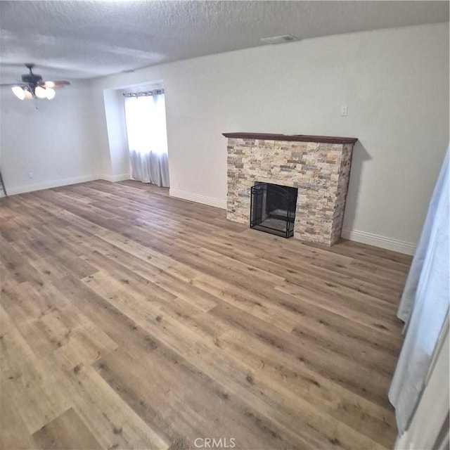 804 S Mayo Ave, Compton, CA 90221 - unfurnished living room featuring wood finished floors, a textured ceiling, visible vents, a fireplace, and ceiling fan