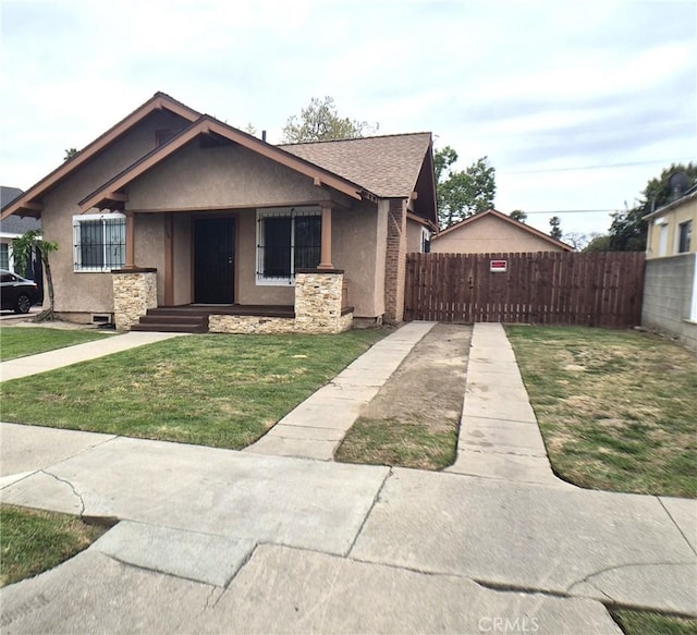 804 S Mayo Ave, Compton, CA 90221 - bungalow-style home with fence, a shingled roof, stucco siding, and a front lawn