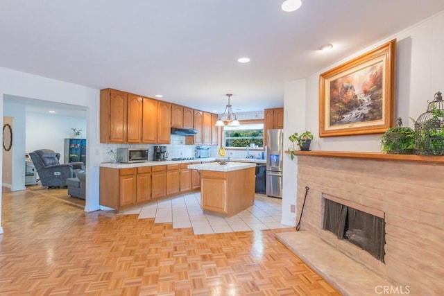 22437 Haynes St, West Hills, CA 91307 - kitchen featuring a kitchen island, stainless steel appliances, under cabinet range hood, light countertops, and decorative backsplash