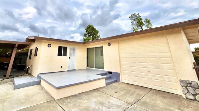 back of house with a garage, a patio area, and stucco siding